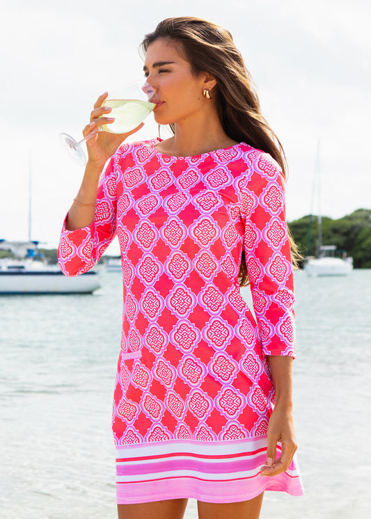 Woman wearing a pink patterned dress by the water
