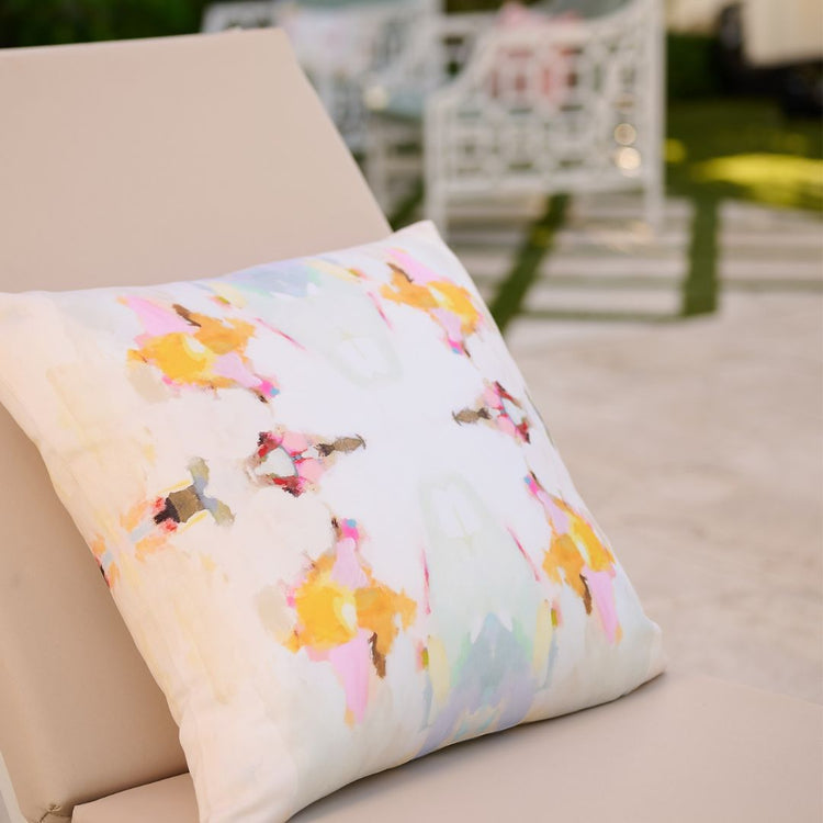 Decorative pillow with colorful floral pattern on a beige sofa outdoors.