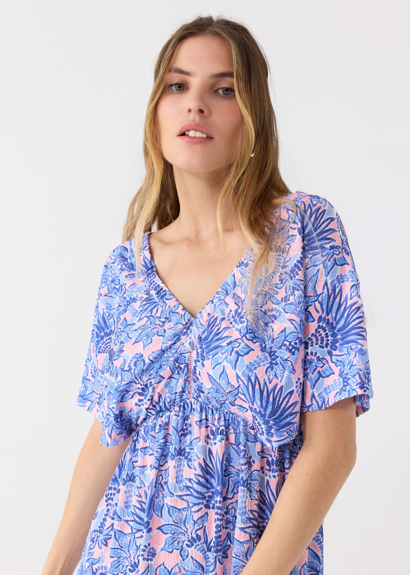 A close up of a blonde woman wearing the Cabana Life sun protective Palm Beach Flutter Sleeve Maxi Dress with a cutout in the middle.