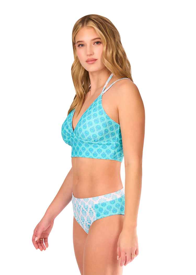 Side of blonde woman wearing Amalfi Coast Reversible Bikini Top with Amalfi Coast Mid Rise Bikini Bottom on white background.