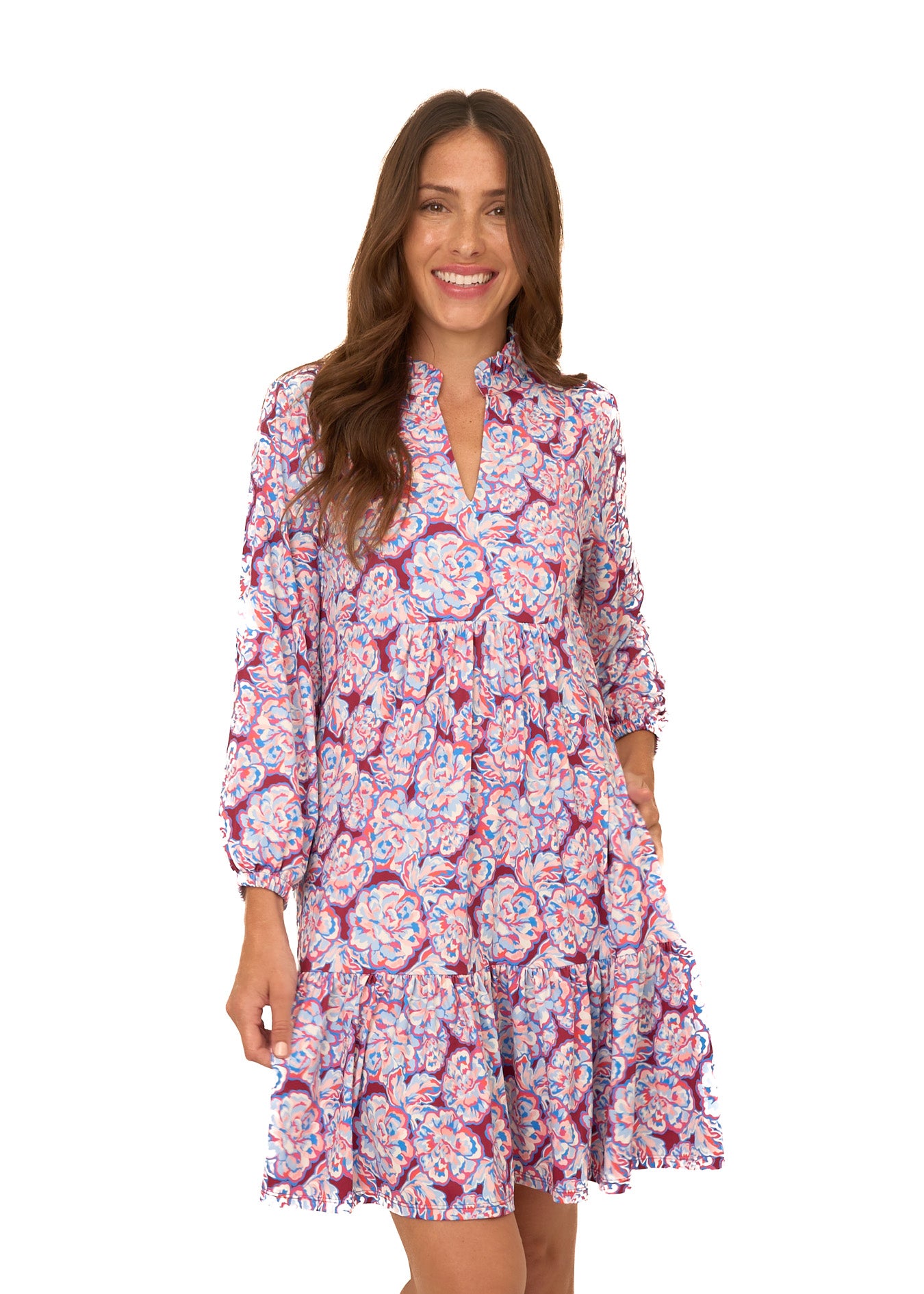 A brunette woman wearing Cabana Life's sun protective Camden Peony Relaxed Dress with her hand in her pocket on a white background.