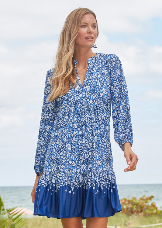 A blonde woman walking at an oceanfront resort wearing Cabana Life's sun protective Seaside Floral Relaxed Dress.