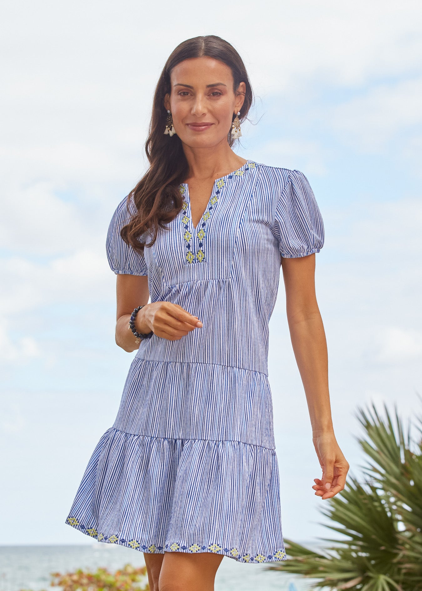 Woman wearing a blue striped dress with a blurred beach background