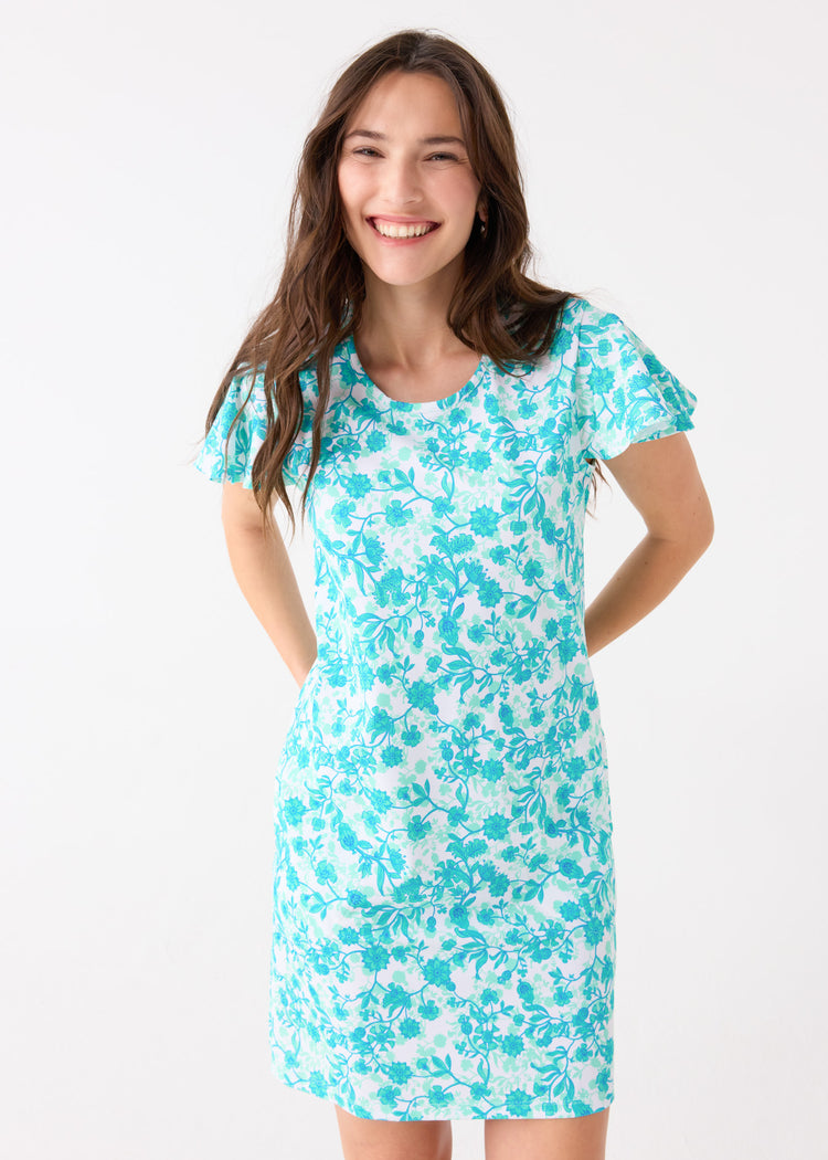 A brunette woman with hands behind her back wearing the Cabana Life sun protective Rosemary Beach Ruffle Short Sleeve Dress.