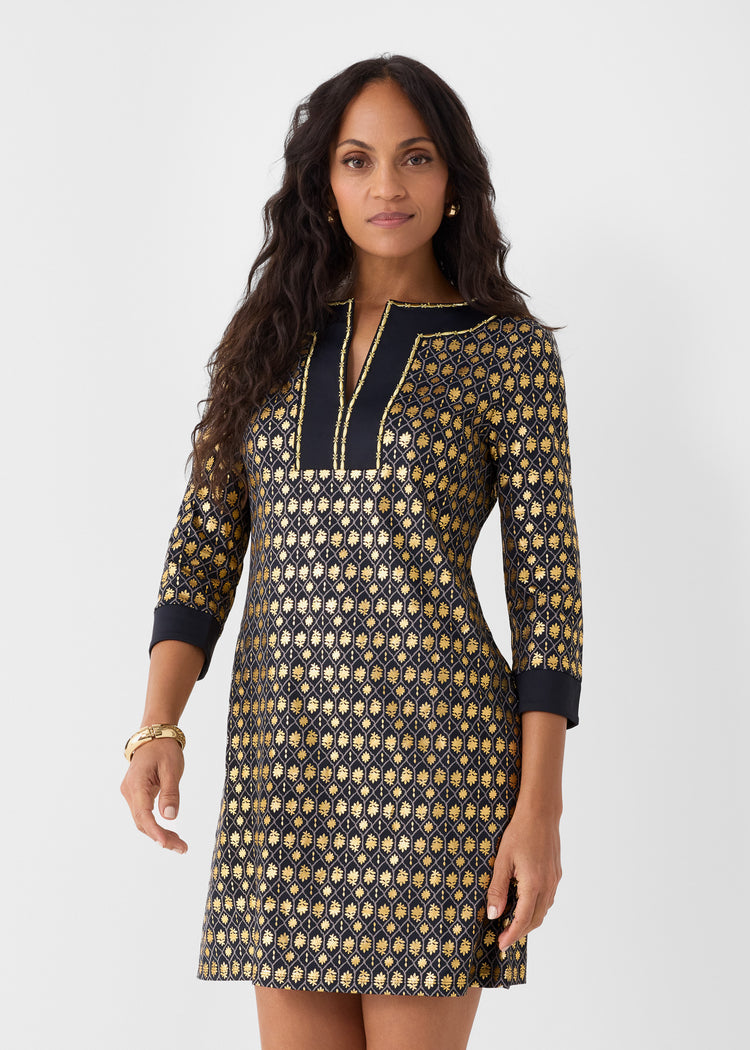 Woman wearing a black and gold patterned dress on a white background