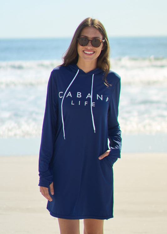 A woman wearing Navy Cabana Life Hoodie Dress with thumbholes and a hand in pocket at the beach.