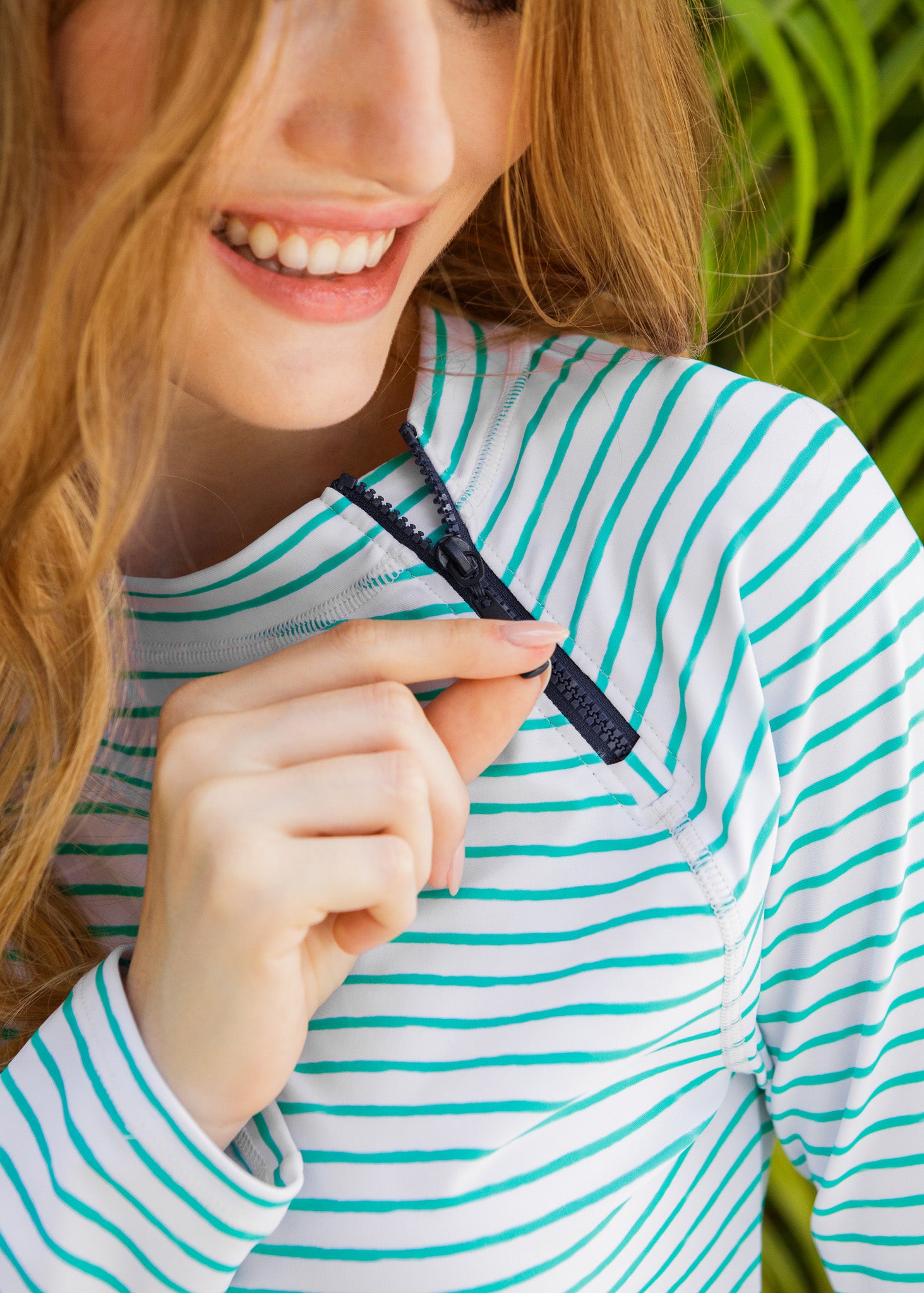 Person wearing a green and white striped rashguard with a close-up of a navy zipper.