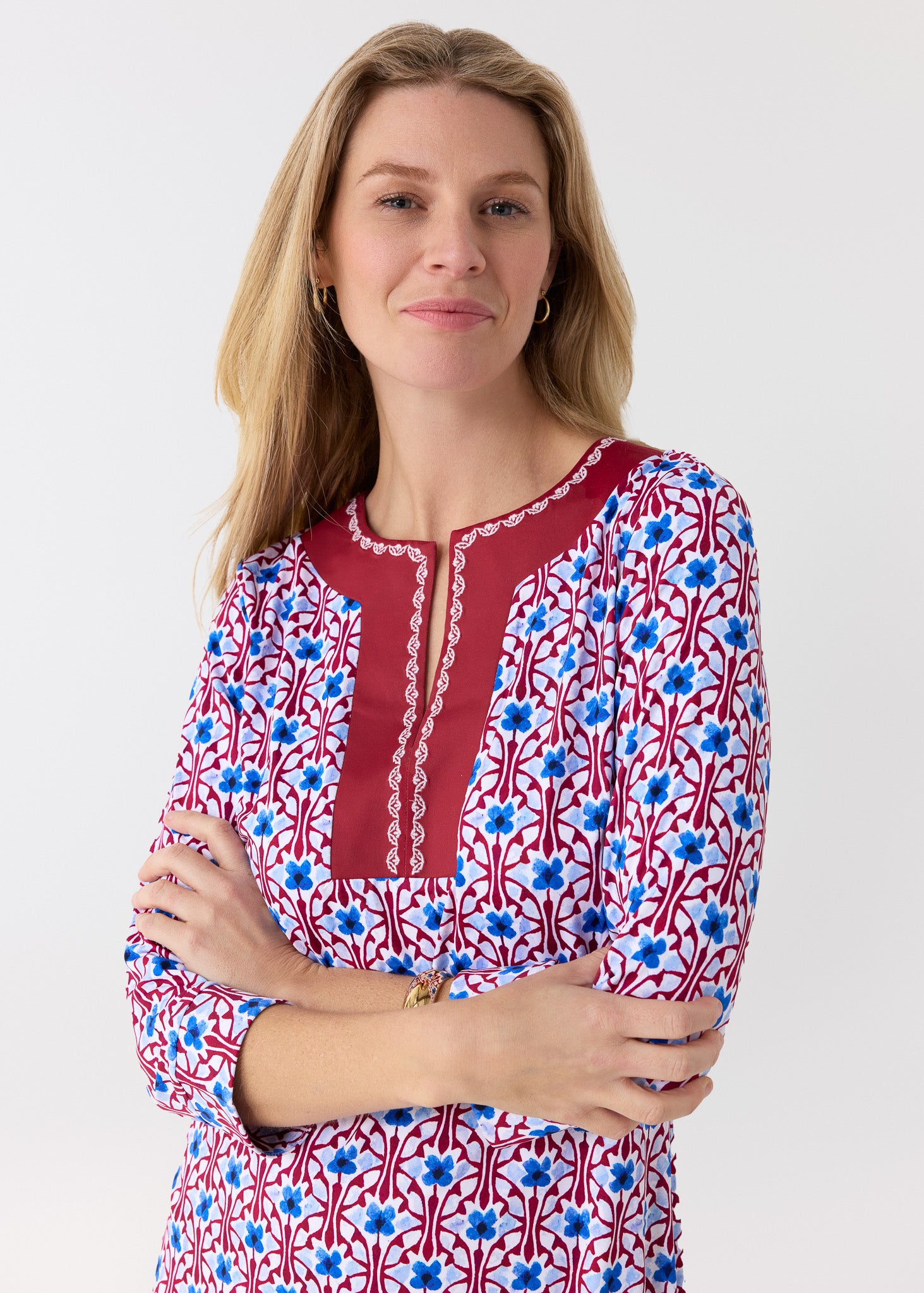 Woman wearing a patterned dress with red, blue, and white design on a white background