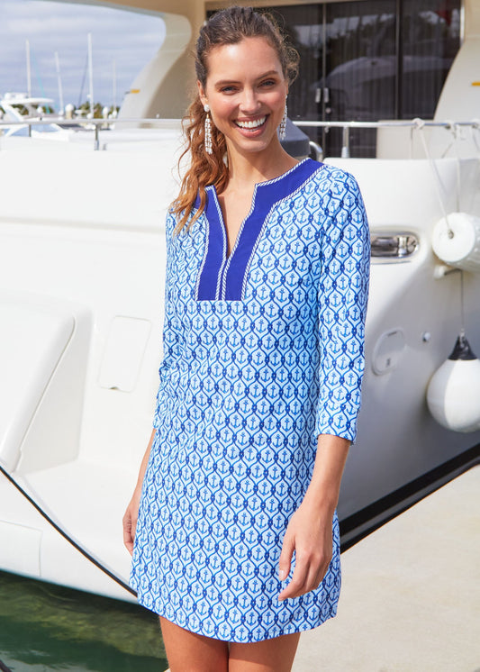 A brunette woman wearing the Cabana Life sun protective Anchor Embroidered Tunic Dress in front of a boat.