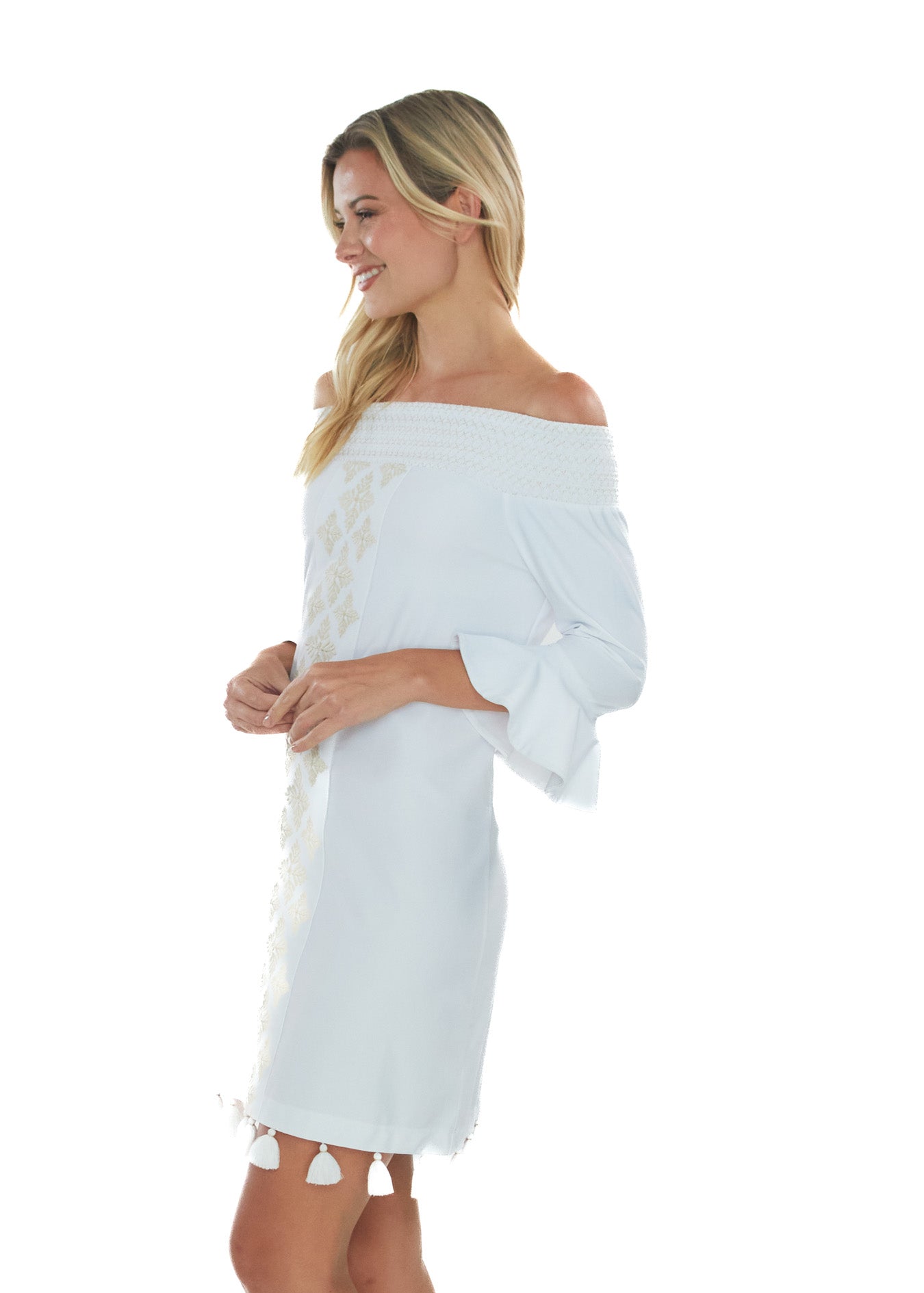 Side facing blonde model wearing the White Embroidered Off The Shoulder Dress while smiling.