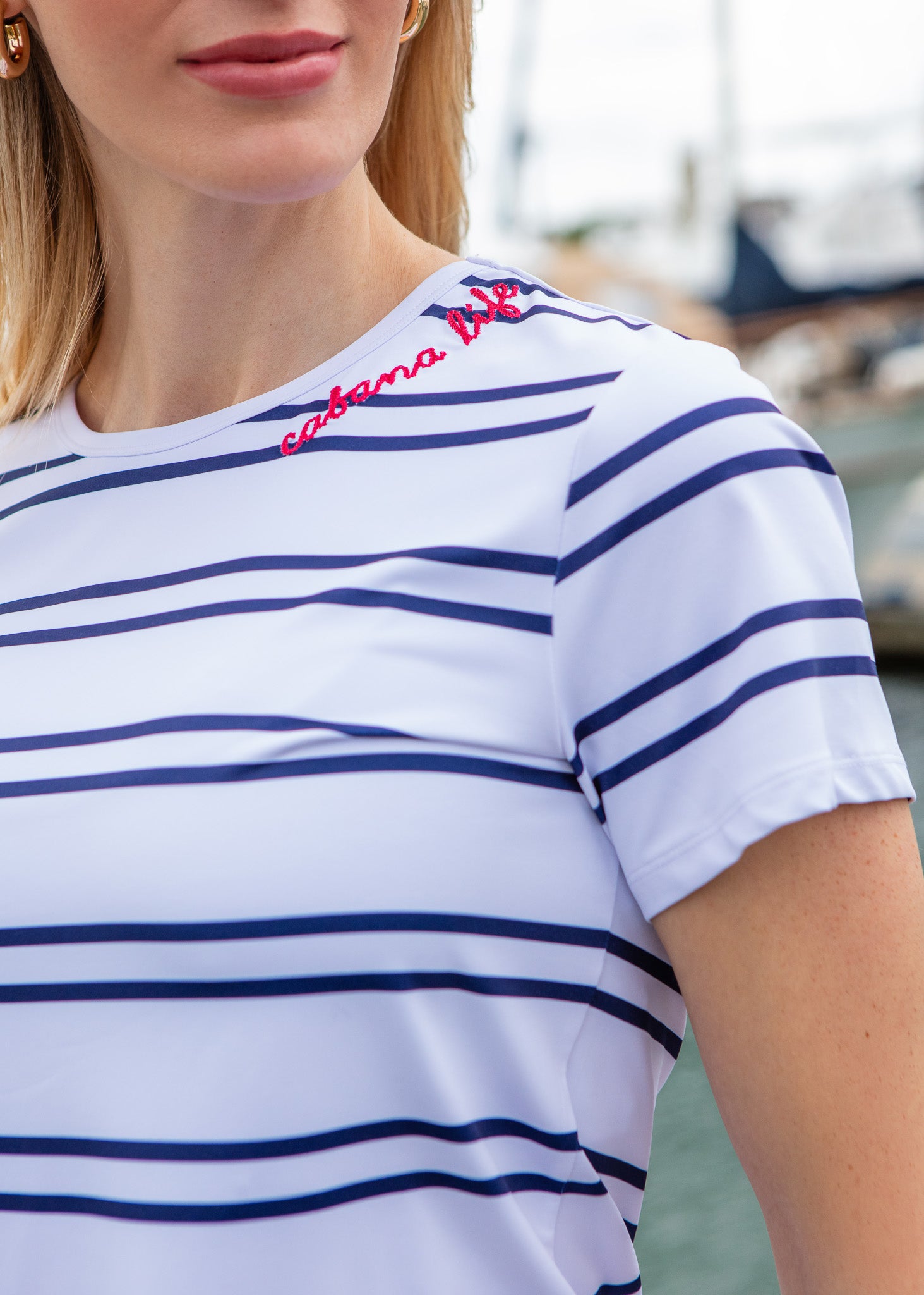Close-up of a person wearing a white and blue striped shirt with red text, blurred background