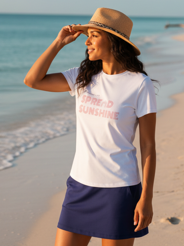 Woman on a beach wearing a 'Spread Sunshine' t-shirt and a hat.