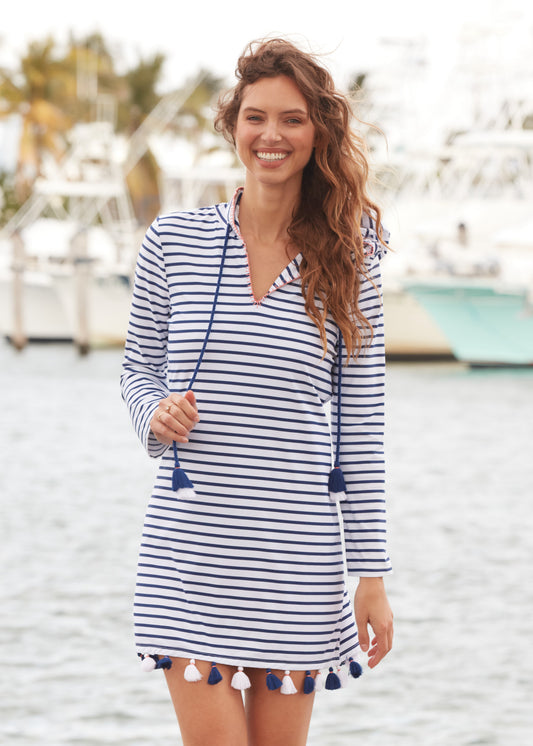 Brunette with curly hair holding tassel of Navy Stripe Hooded Cover Up in front of marina.