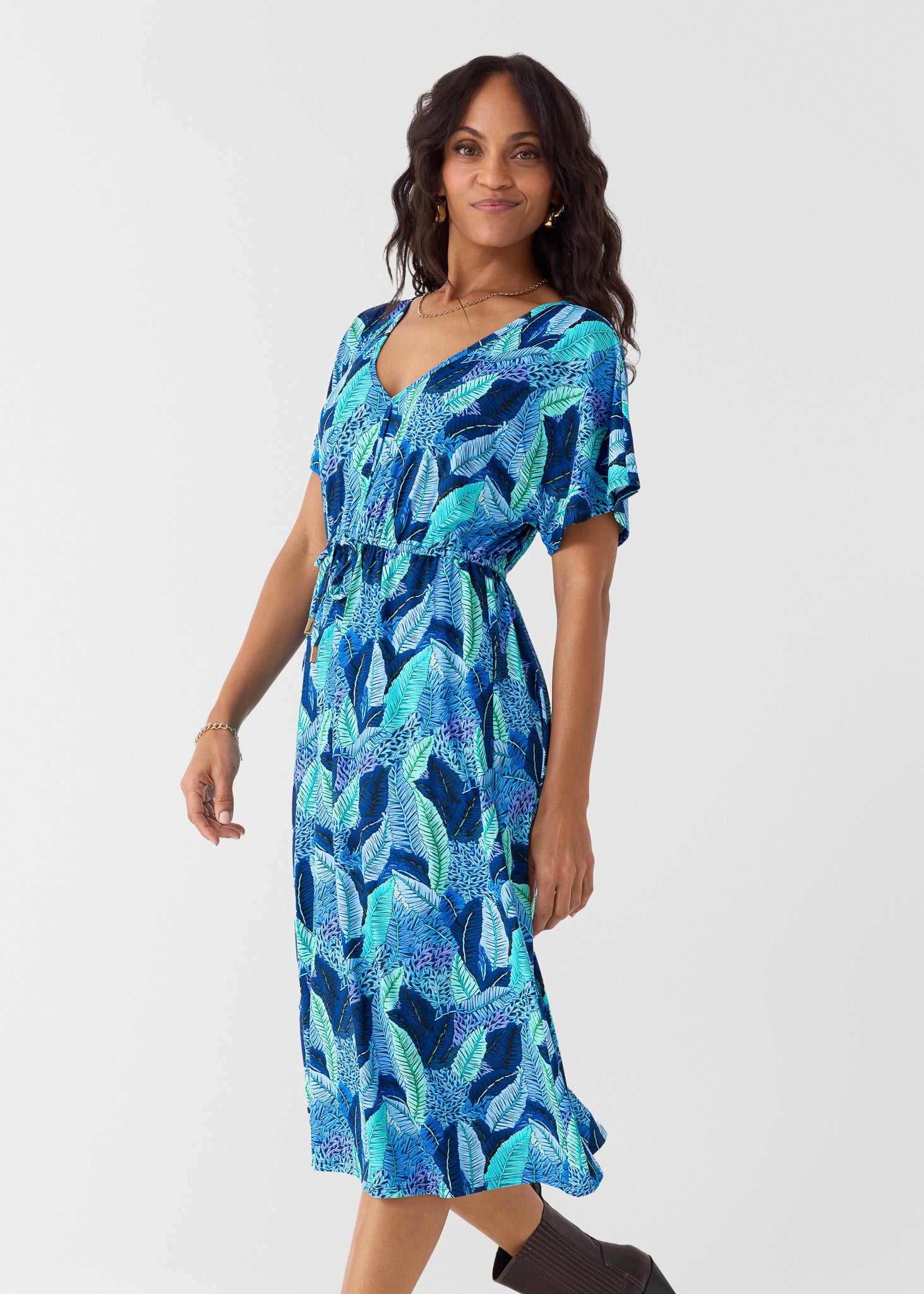 Woman wearing a blue and green patterned dress on a white background