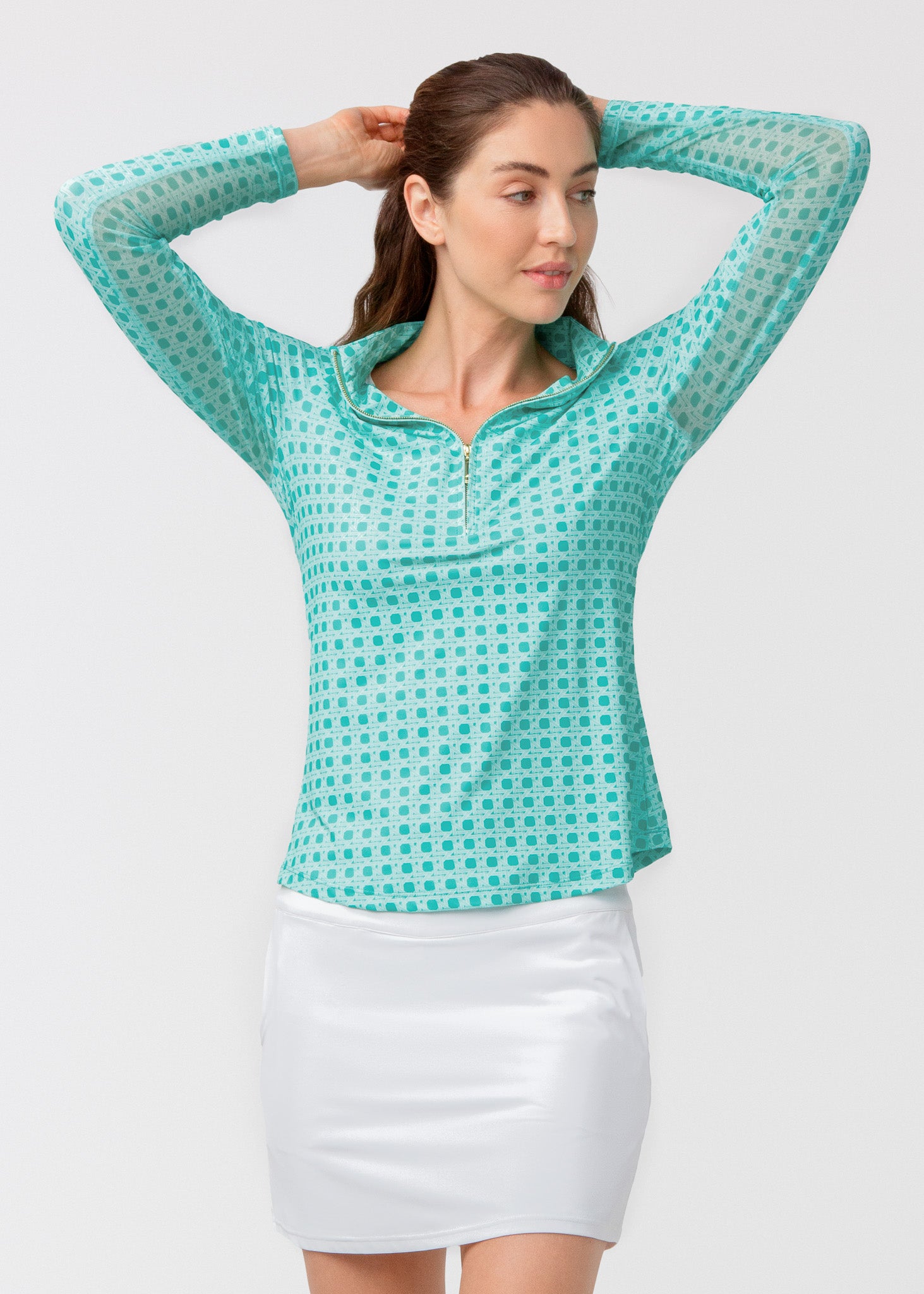 Woman wearing a green basketweave shirt and white skirt on a light gray background