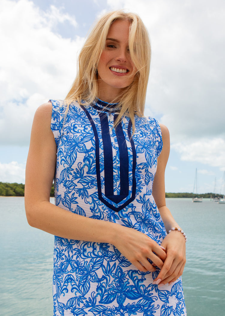 Woman wearing a blue and white floral dress by a body of water.