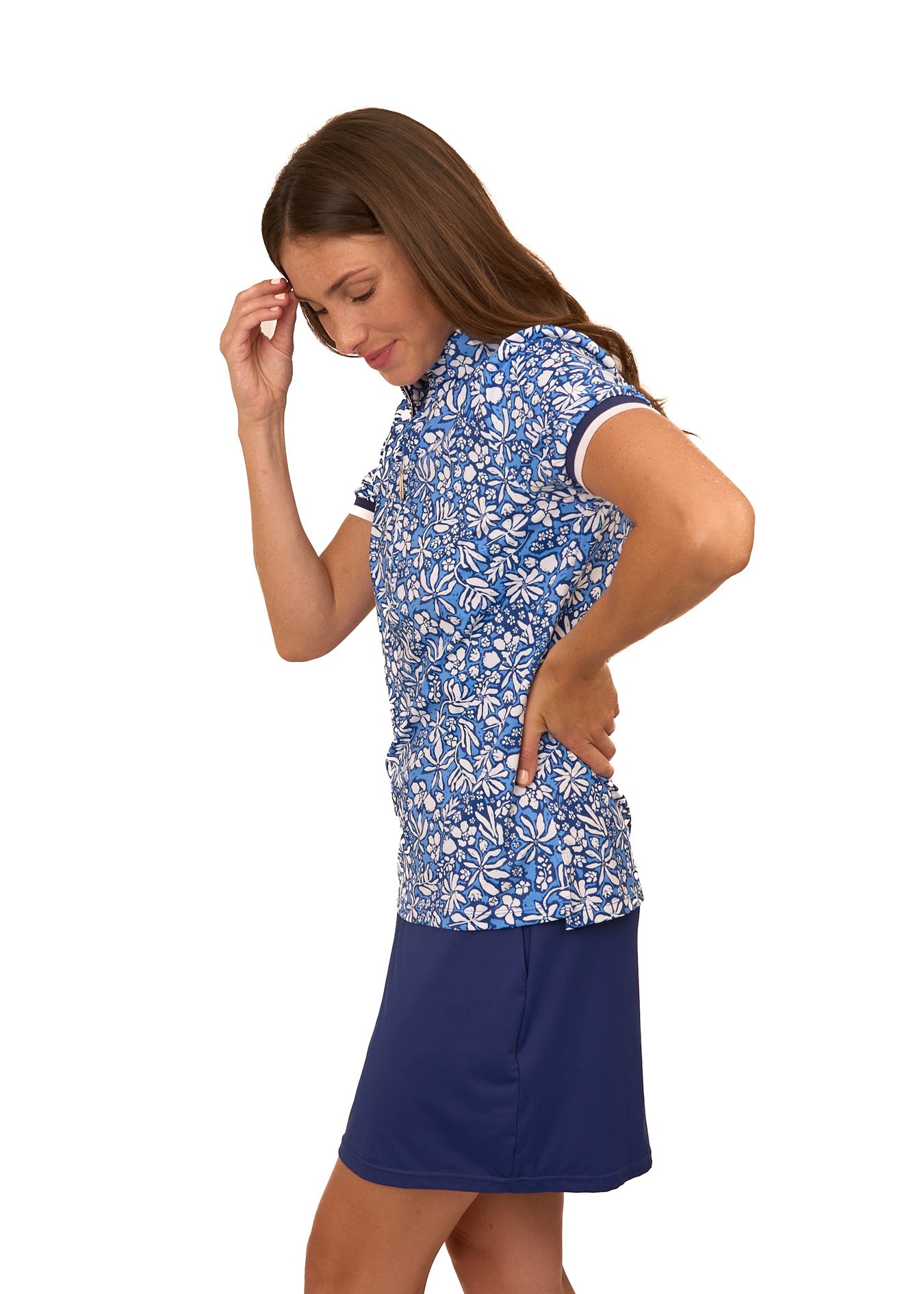 The side of a brunette woman wearing the sun protective & navy floral Seaside Short Sleeve Collared 1/4 Zip and Navy Skort from Cabana Life on a white background.
