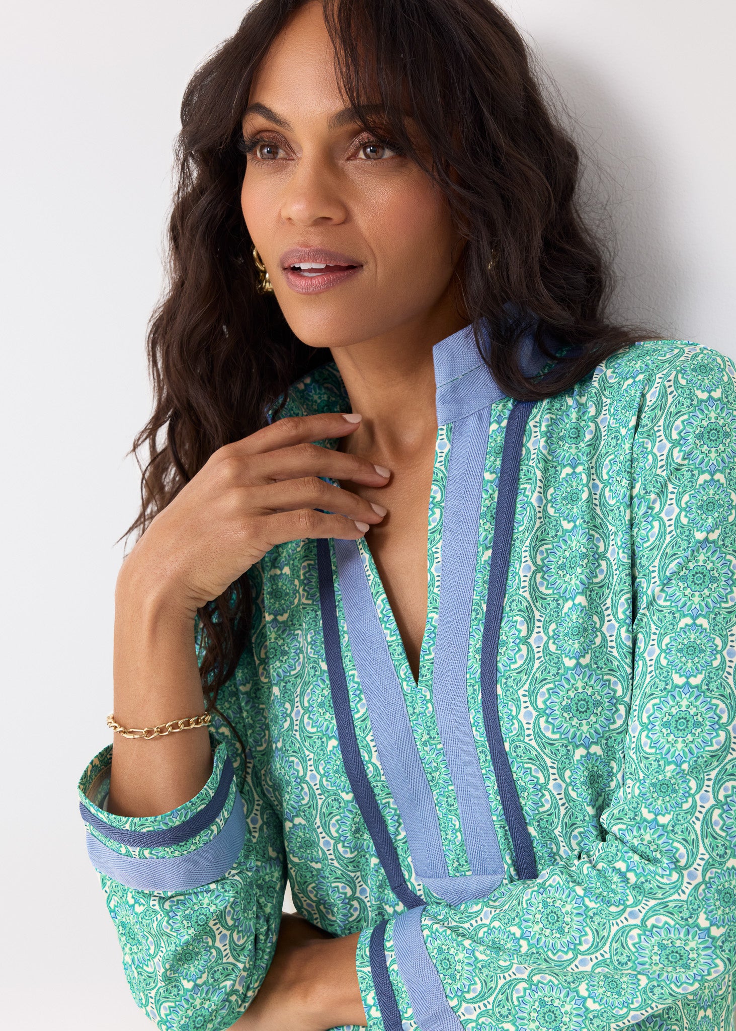 Woman wearing a green and blue patterned outfit against a white background