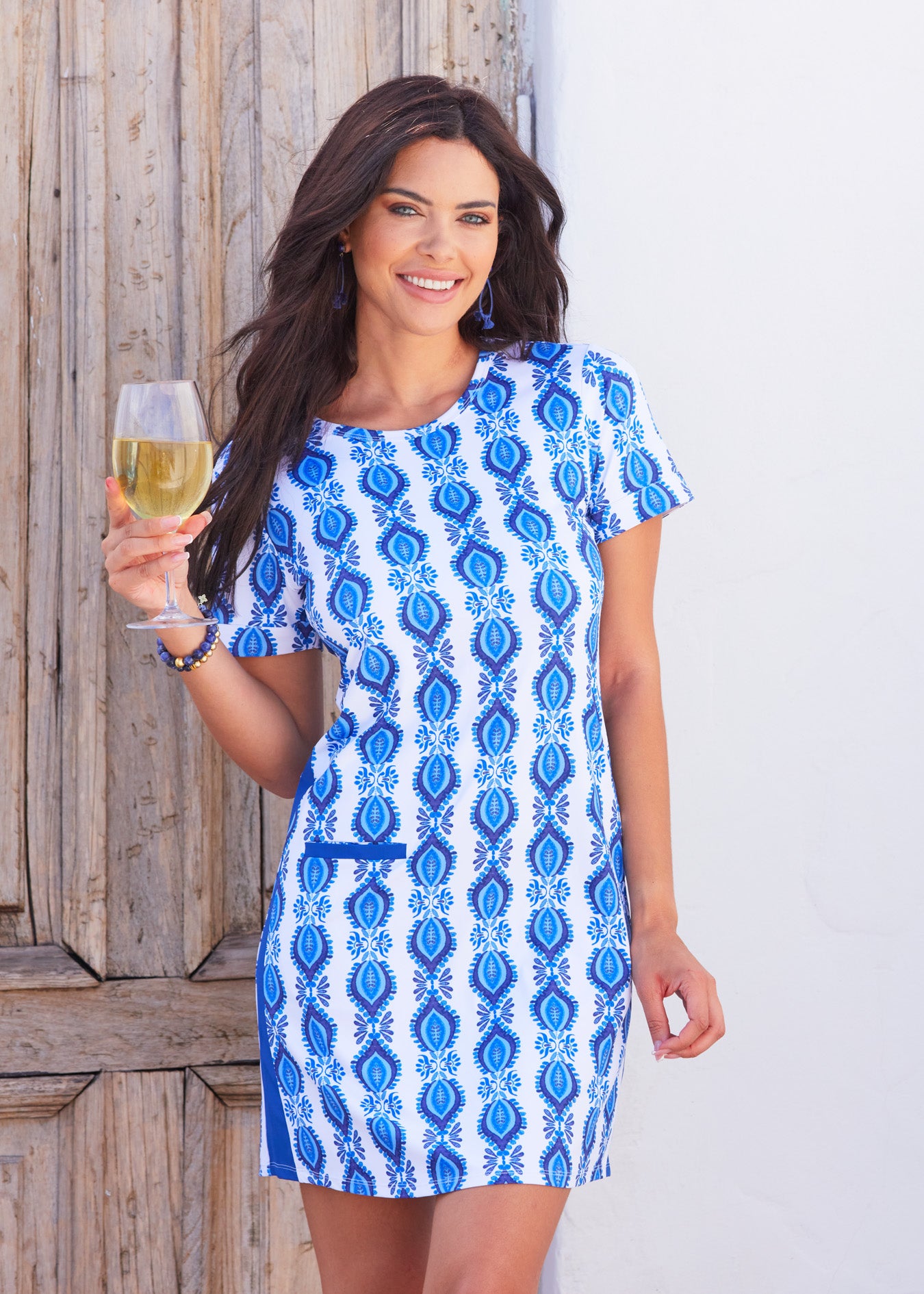 Woman smiling wearing San Sebastian Short Sleeve Tee Dress holding white wine glass