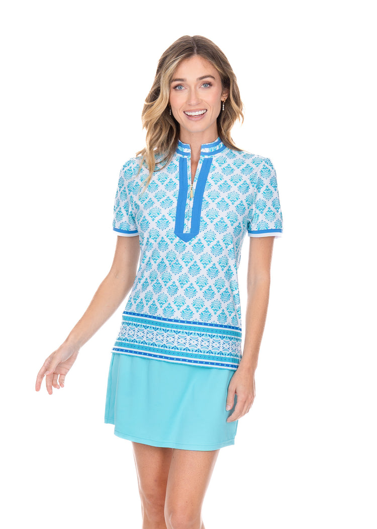 Blonde woman wearing the Amalfi Coast Short Sleeve Collared Quarter Zip with a aqua colored skort. 