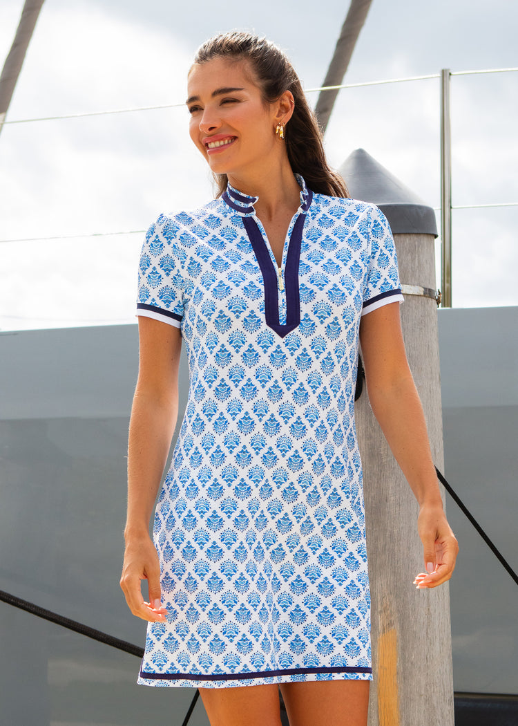 Woman wearing a blue and white patterned dress standing on a boat.