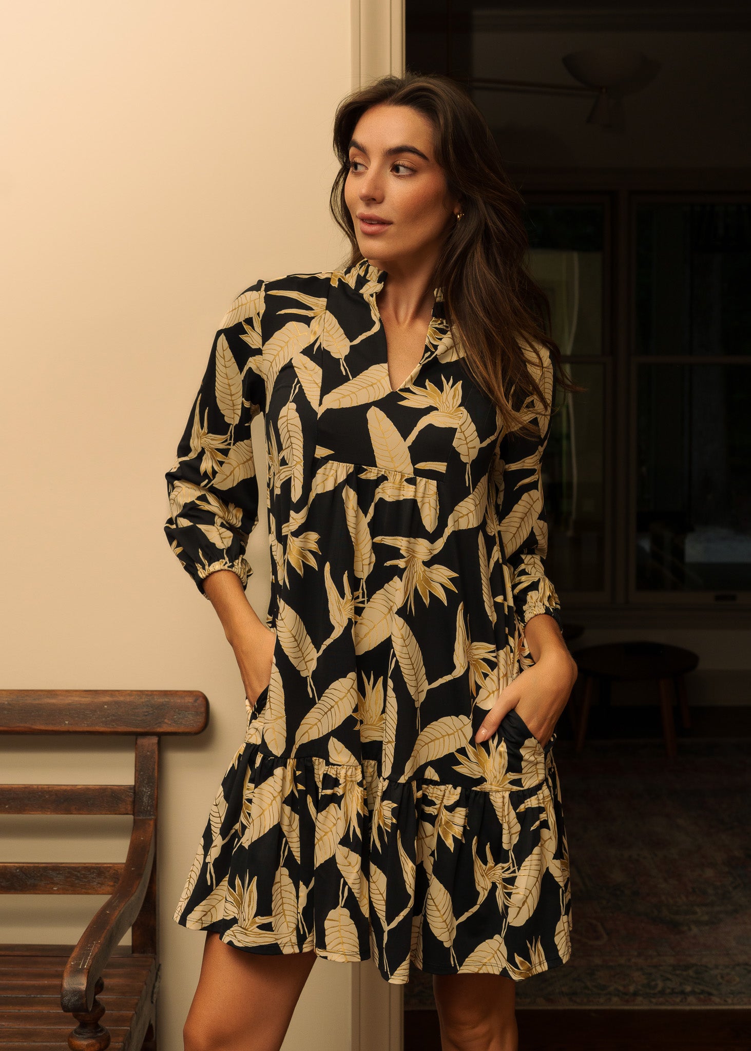 Woman wearing a black and gold patterned dress indoors.