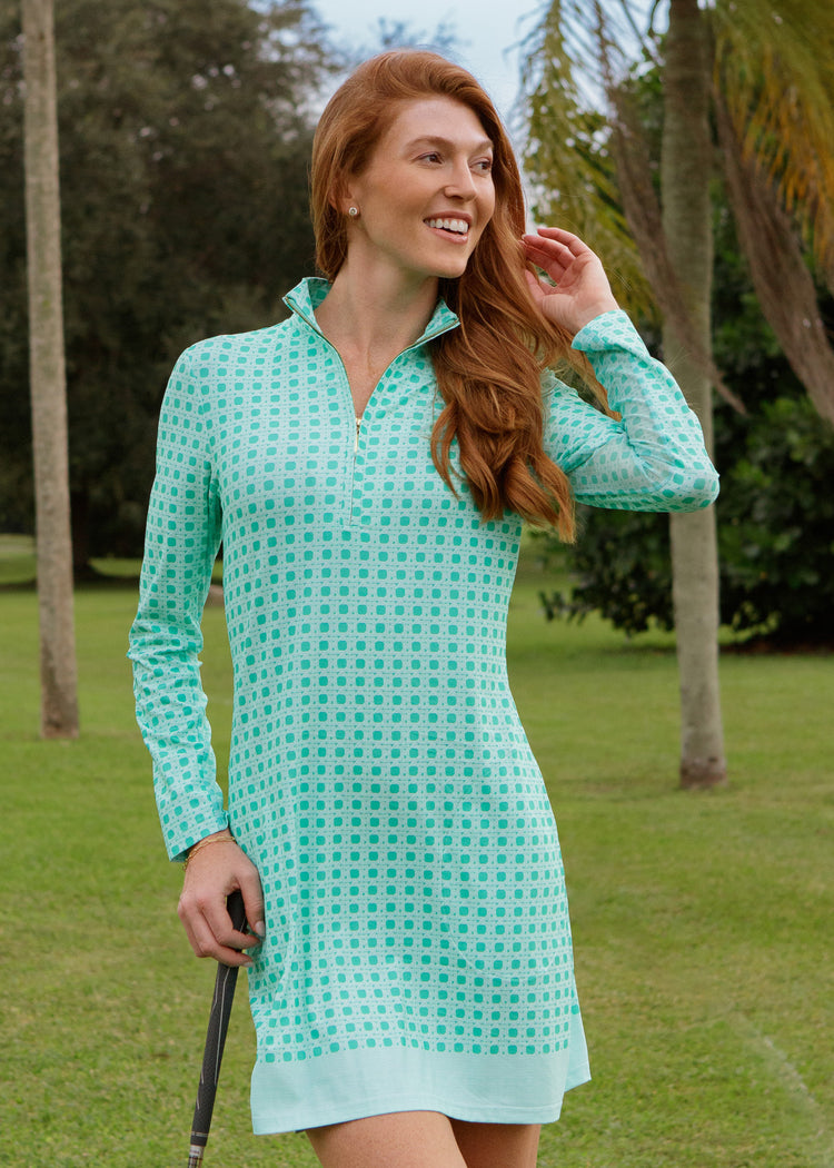 Woman wearing a green basketweave dress standing on a golf course.