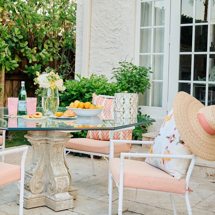 Outdoor patio setting with a glass table, chairs, and decorative elements.