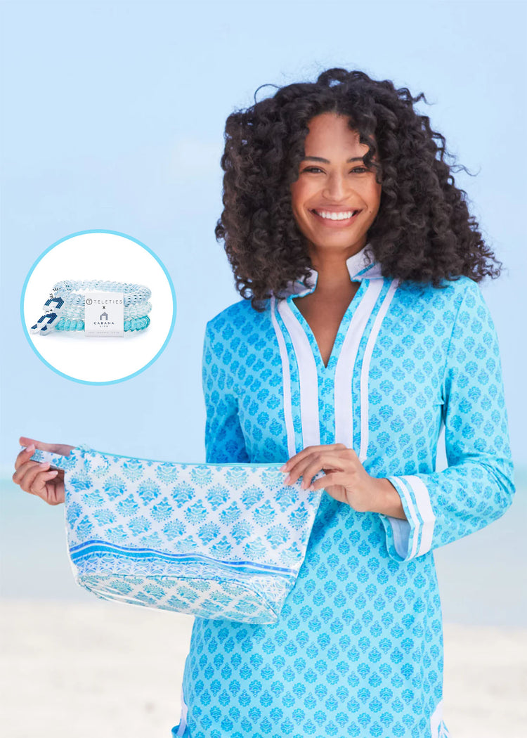 Woman smiling wearing Amalfi Coast Tunic Dress opening Amalfi Coast Large Accessory Bag with a the Amalfi Coast Cabana Life x Teleties Hair Tie 3-Pack on top.