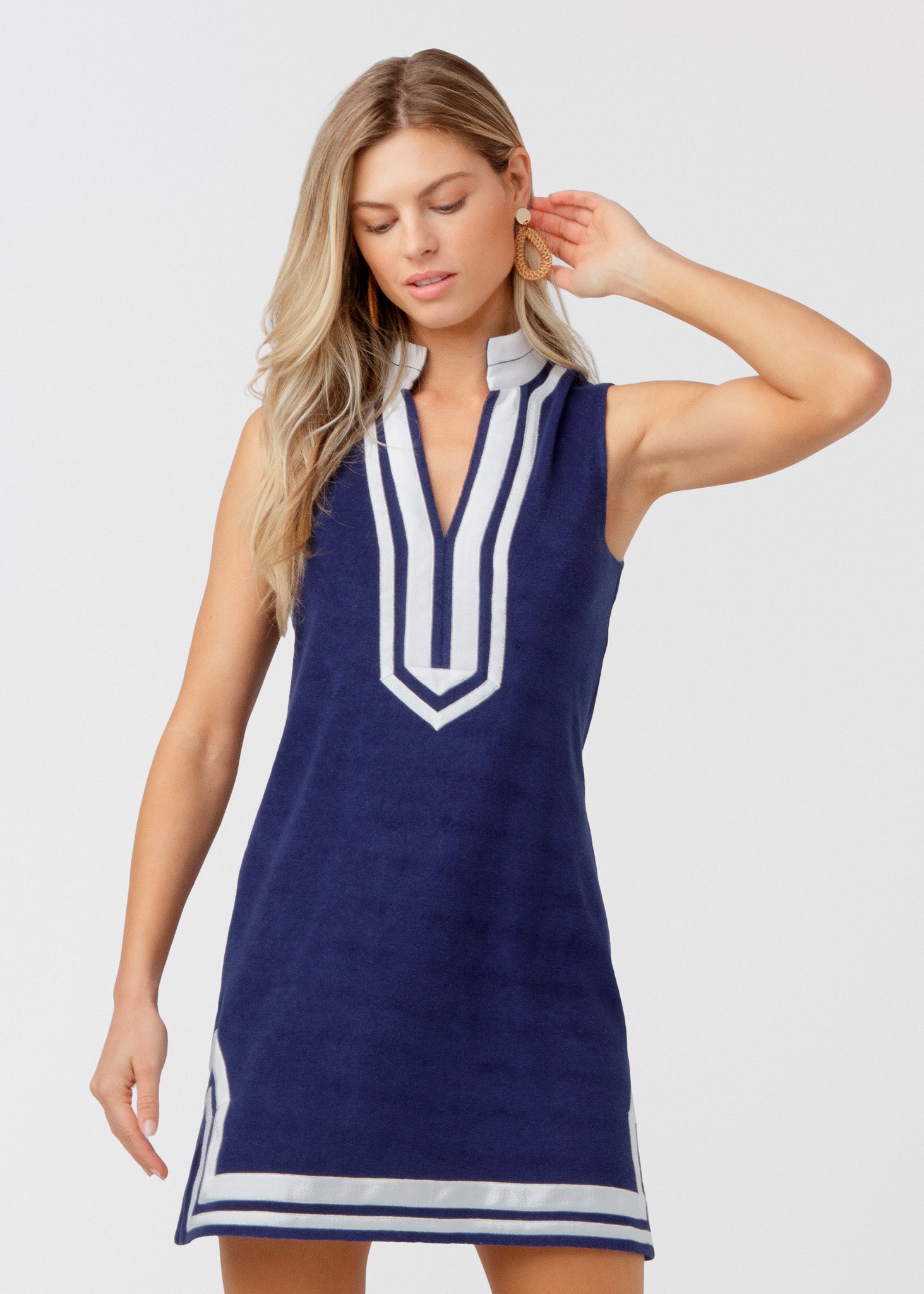 Woman wearing a navy dress with white accents on a white background