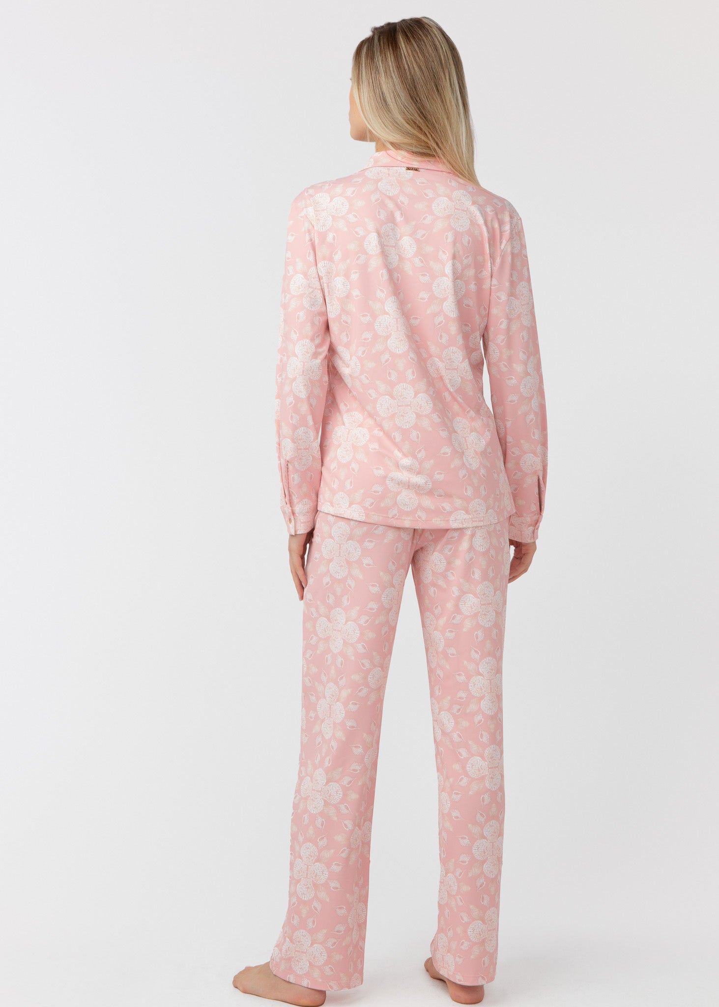 Woman standing with her back facing, wearing our Coast pink and white shell patterned sleep to street pajama set on a white background.
