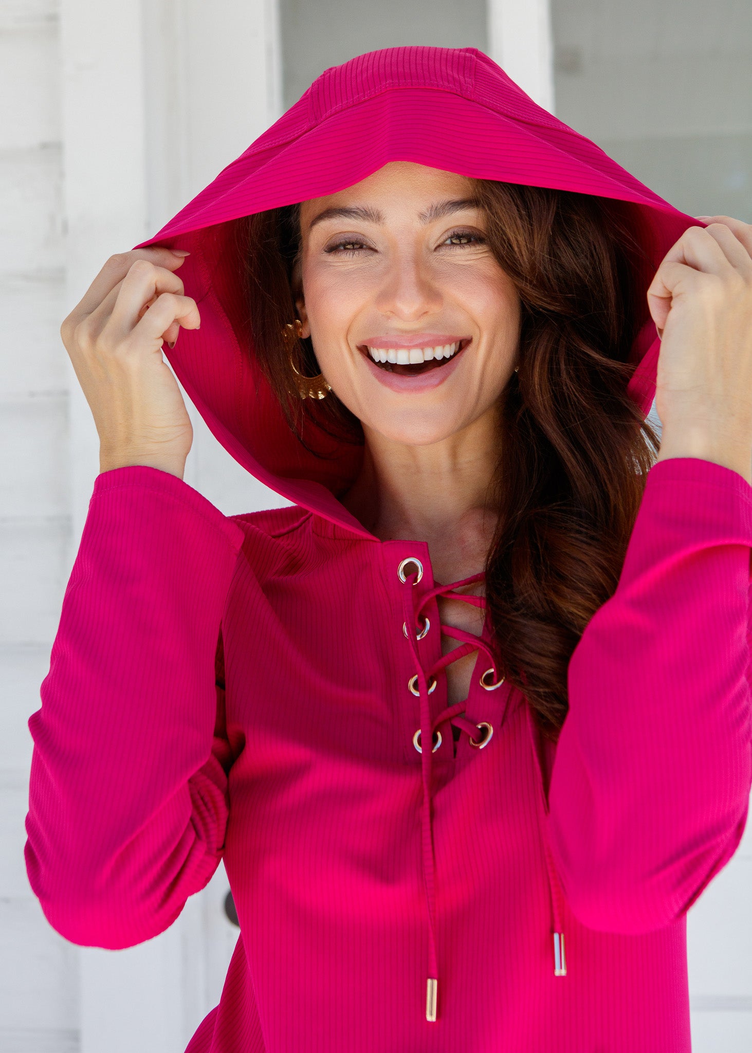 Woman wearing a bright pink cover up with a white background