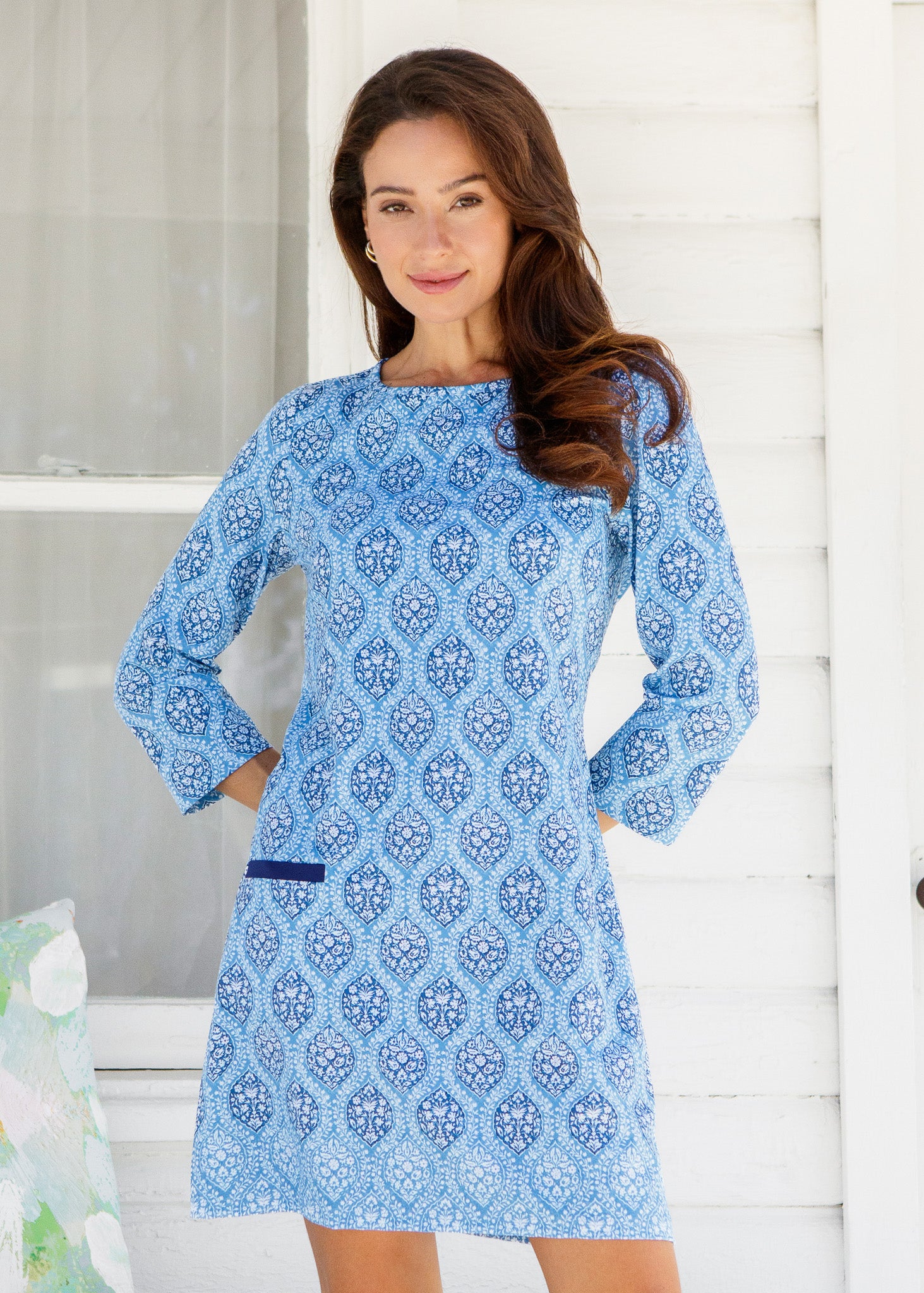 Woman wearing a blue patterned dress against a white background