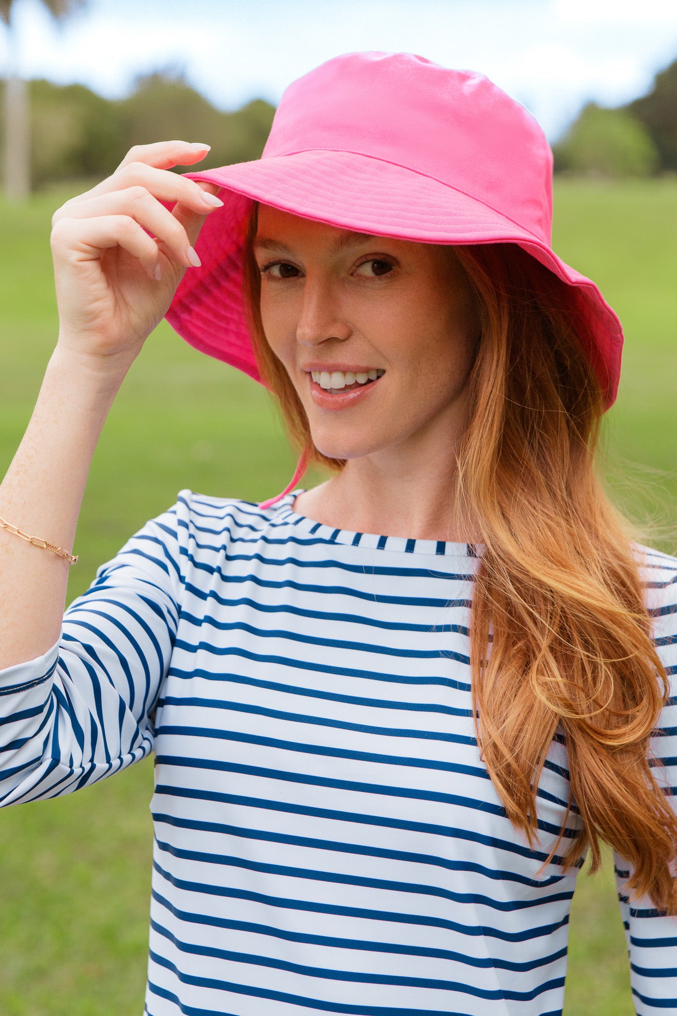 Woman wearing a pink hat and dress shirt outdoors