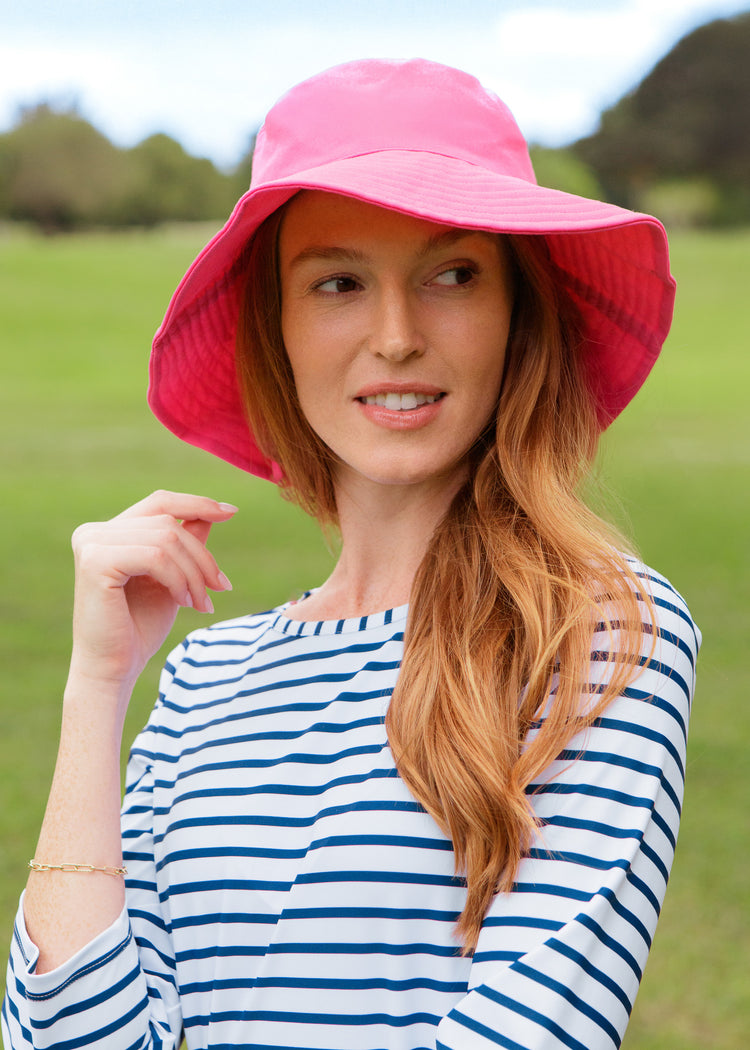 Woman wearing a pink sun hat and striped dress outdoors
