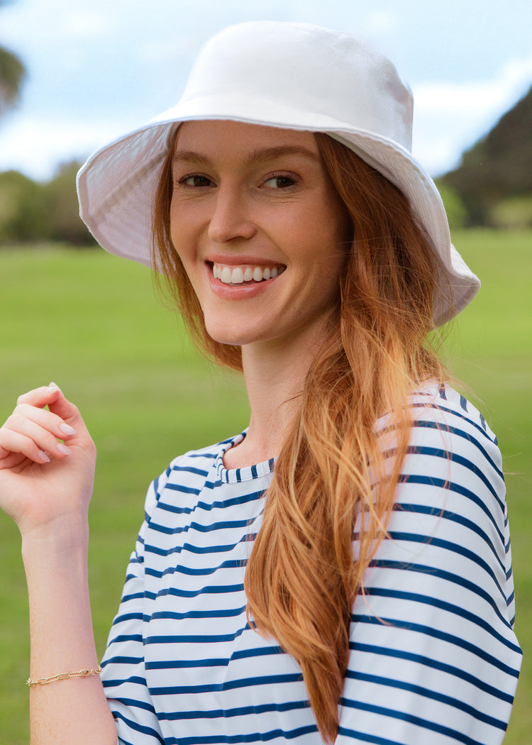 Woman wearing a white bucket hat and striped dress in an outdoor setting