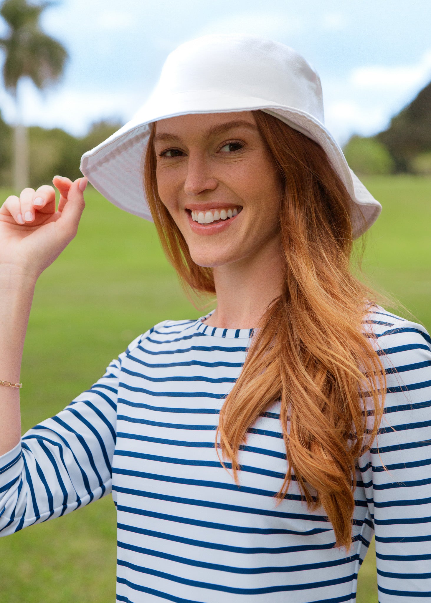 Woman wearing a white bucket hat and striped dress outdoors
