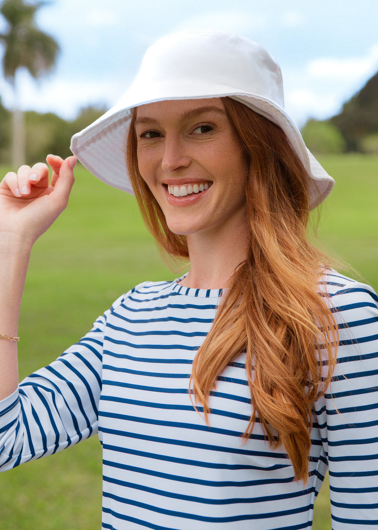 Woman wearing a white bucket hat and striped dress outdoors