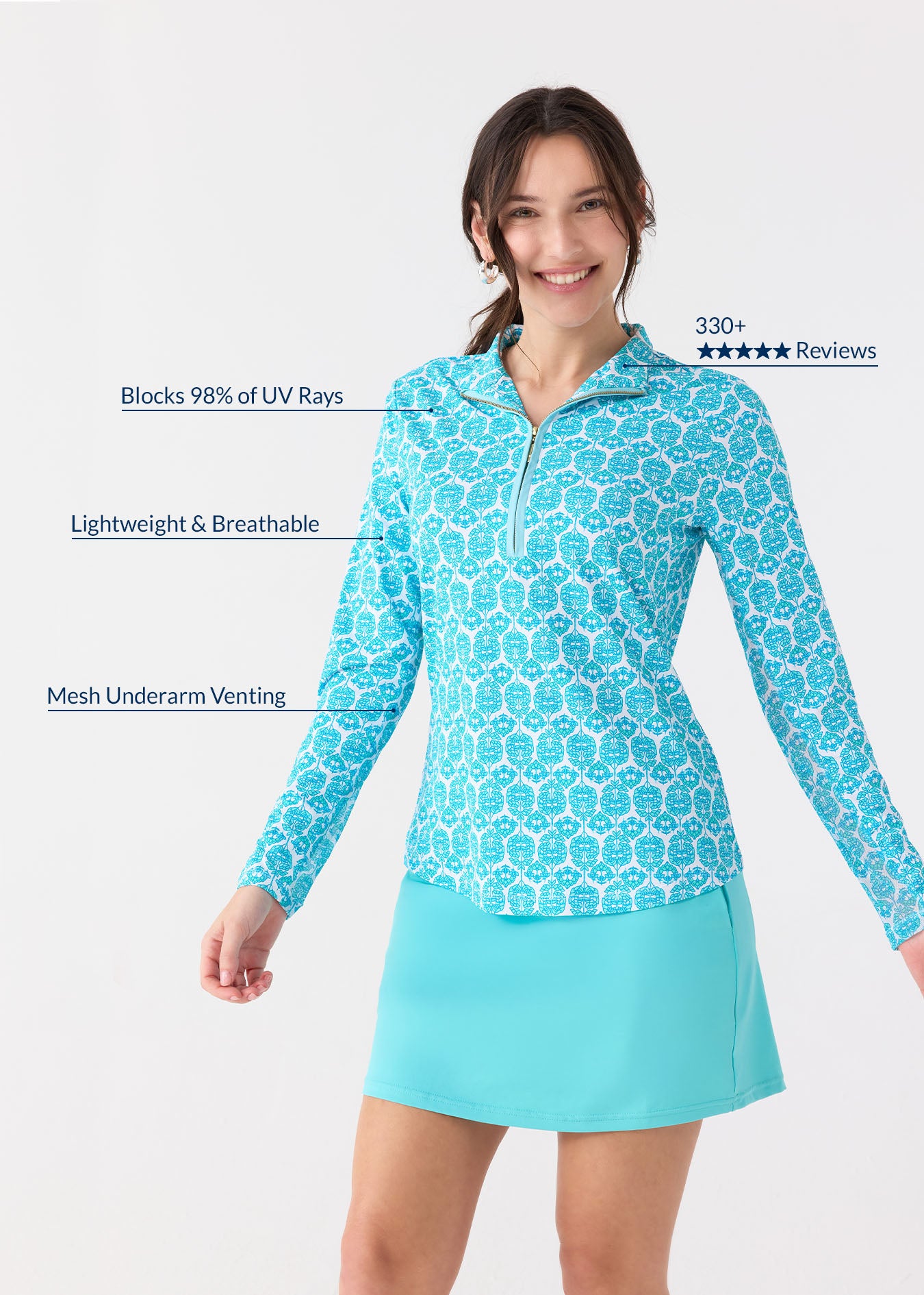 A brunette woman smiling wearing the Cabana Life sun protective Rosebay Performance 1/4 Zip Sport Top with mesh underarms, paired with the Aqua 17" Skort.