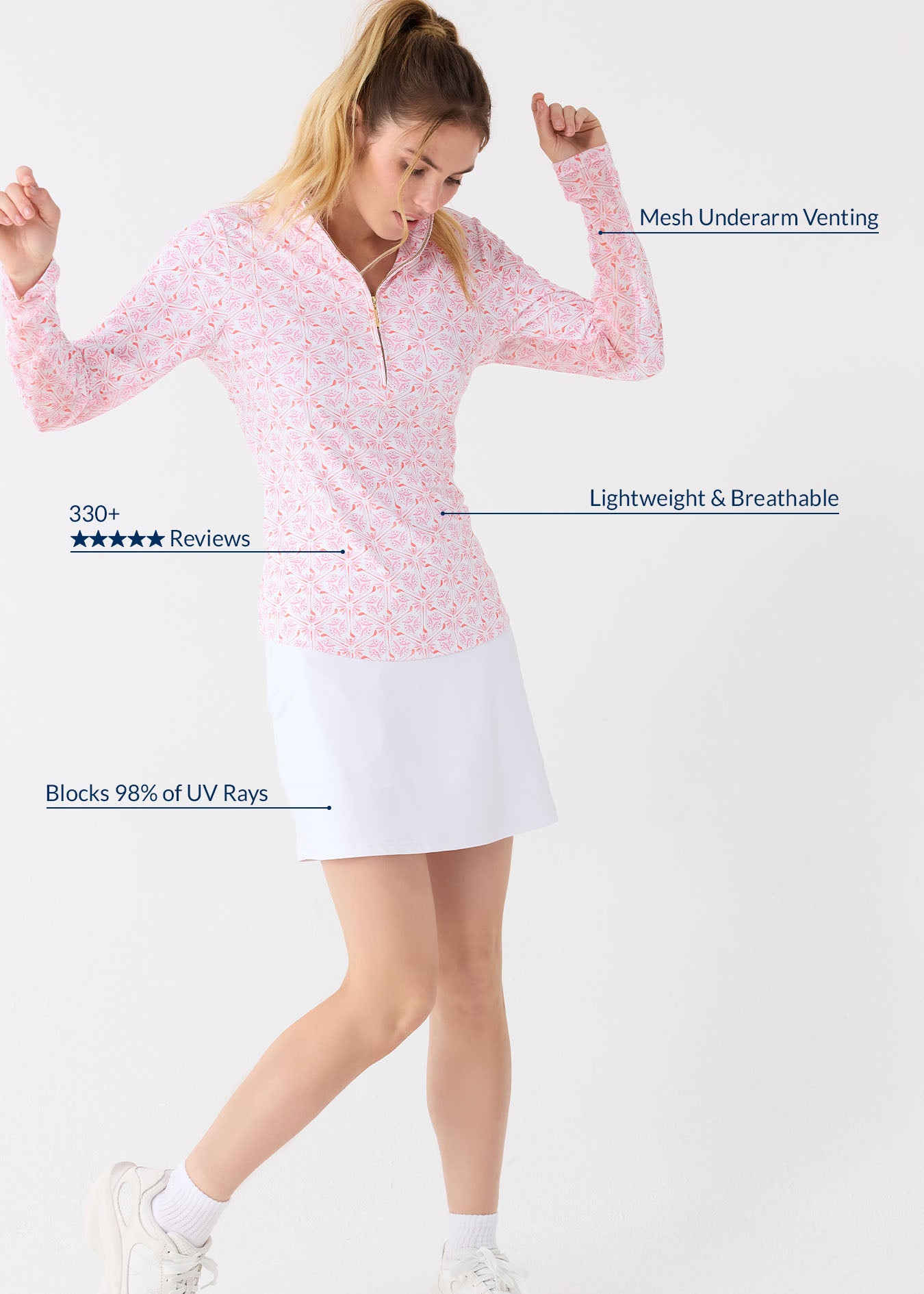 A blonde woman dancing wearing the Cabana Life sun protective Golf 1/4 Zip Sport Top with printed mesh underarm venting and the White 17" Skort.