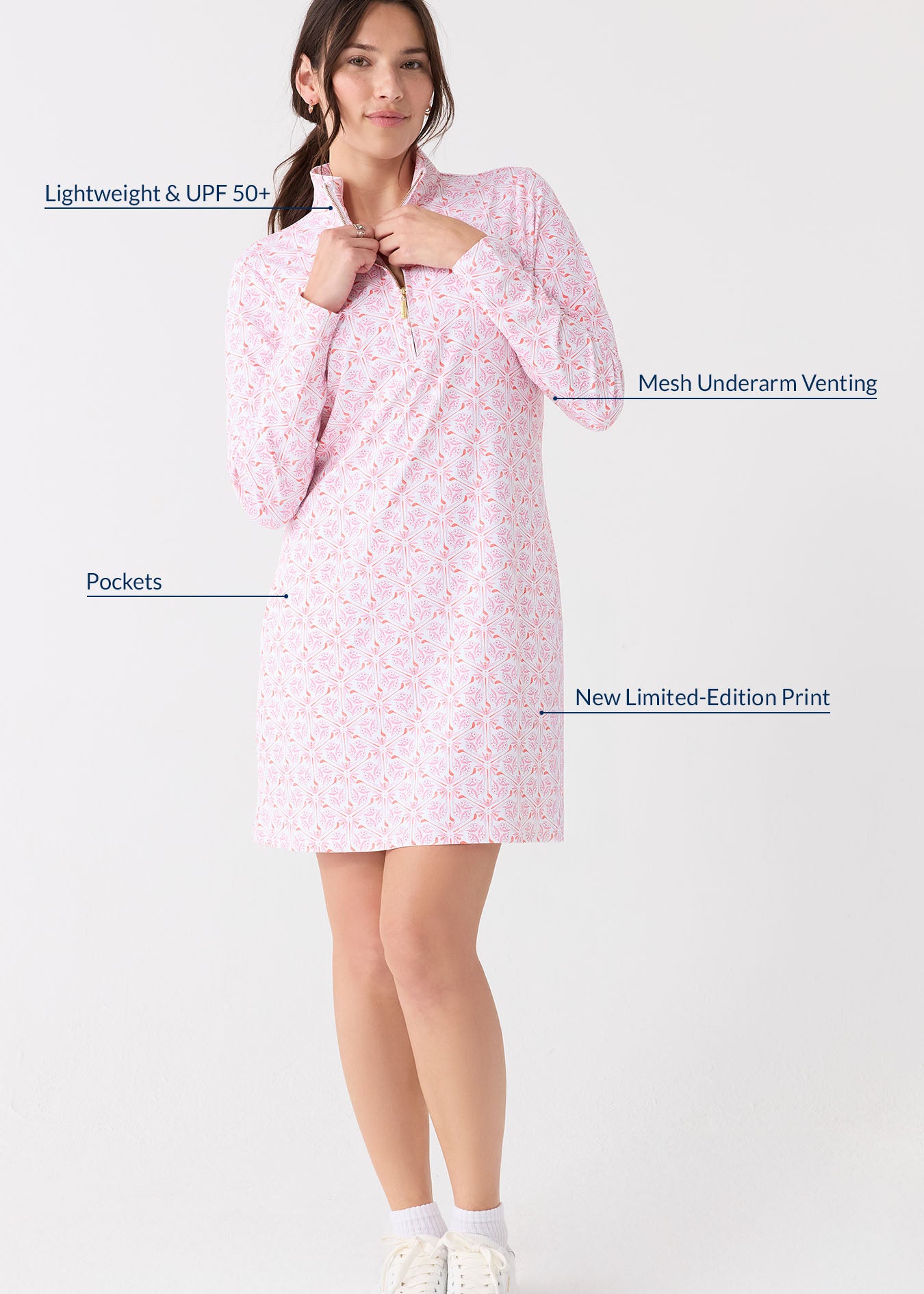 A brunette woman touching the collar of the Cabana Life sun protective Golf 1/4 Zip Sport Dress and wearing white sneakers and socks.