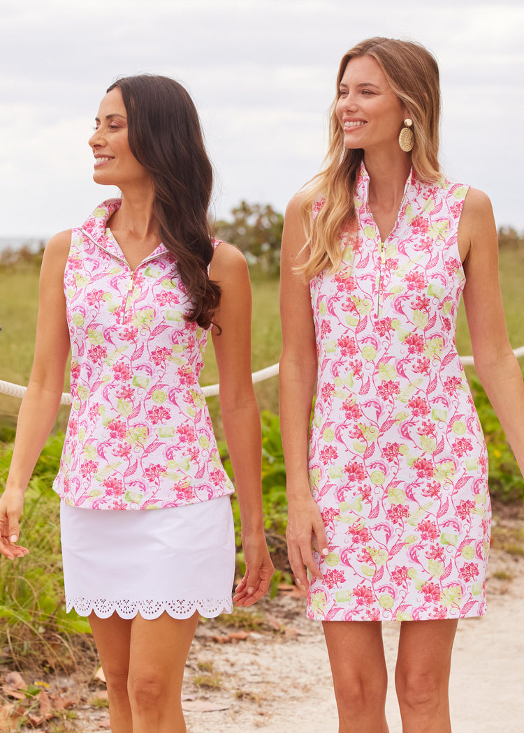 A brunette woman wearing the Cabana Life sun protective Margarita 1/4 Zip Sleeveless Sport Top and White 15" Scallop Skort walking with a women wearing the Margarita 1/4 Zip Sleeveless Sport Dress.