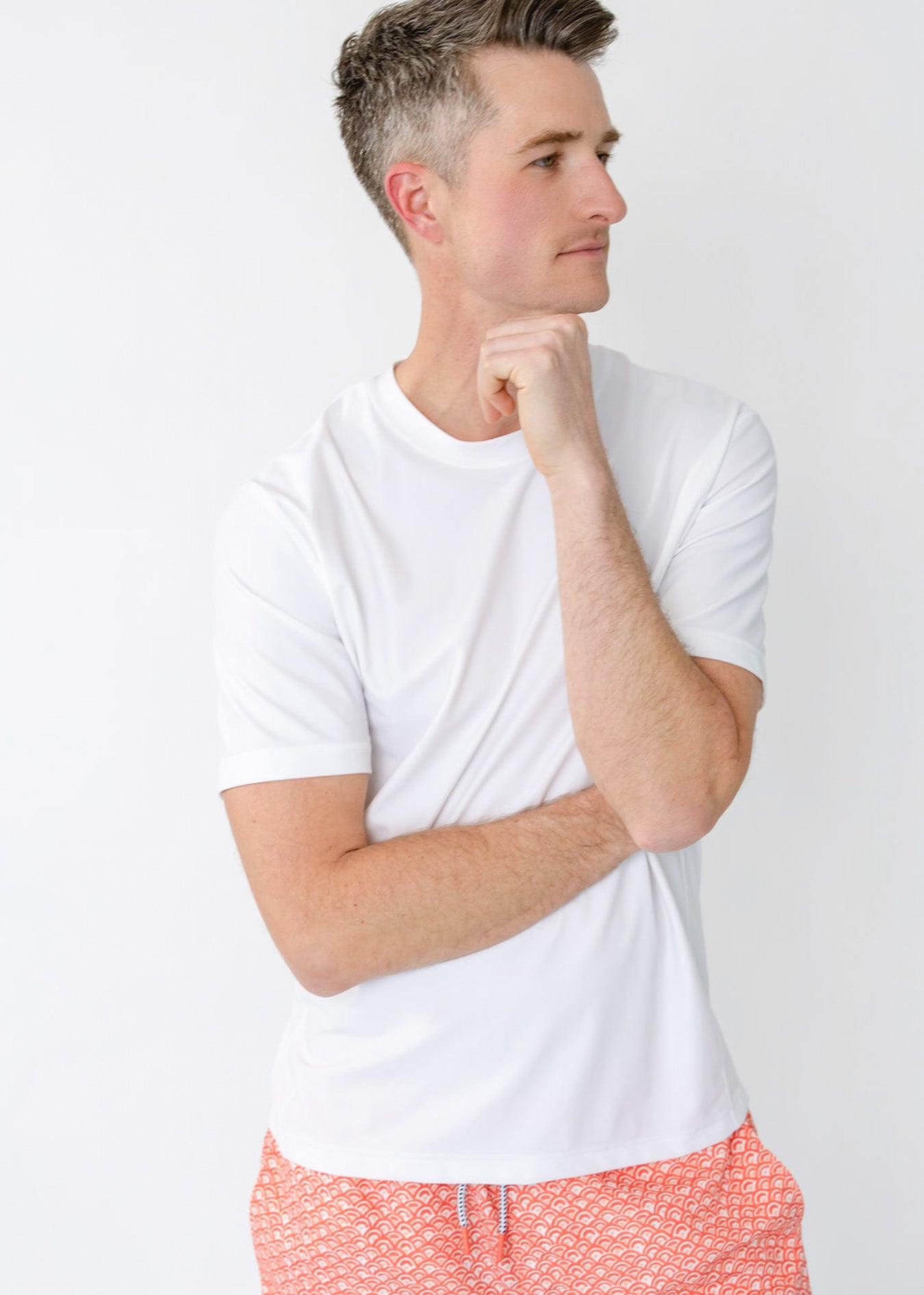 A man wearing the sun protective Men's White Short Sleeve Rashguard with the Men's Amelia Island Swim Trunk from Cabana Life.