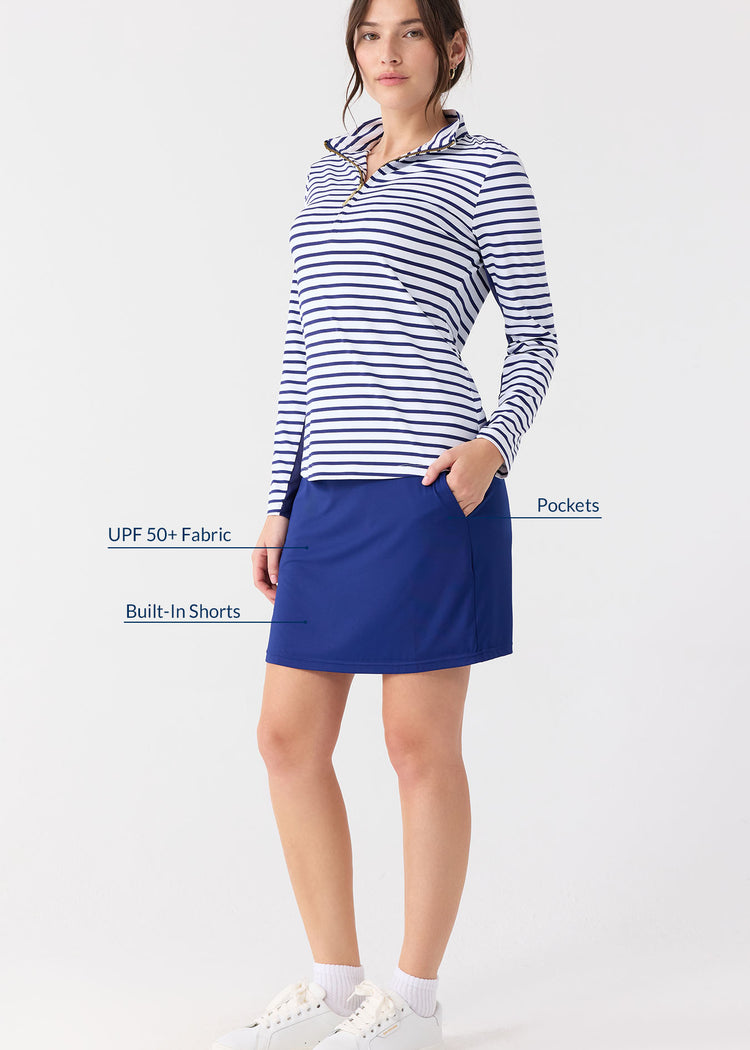 Woman wearing a striped long-sleeve top and blue skirt with text highlighting features on a white background
