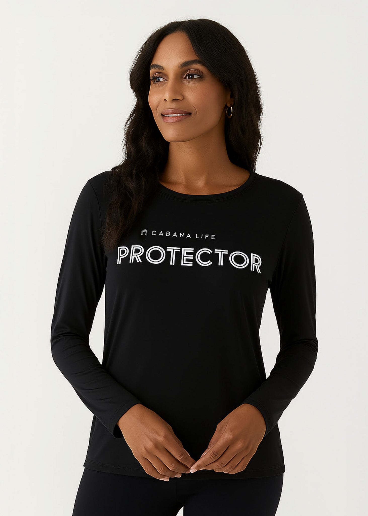 Brunette woman in a studio wearing our sun safe Black Unisex Long Sleeve Protector Performance Shirt.