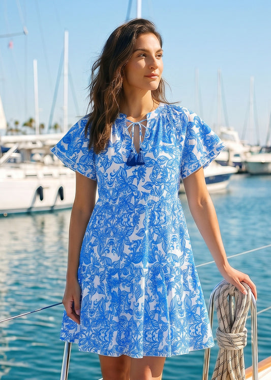 Woman wearing a blue and white floral dress on a boat in a marina.