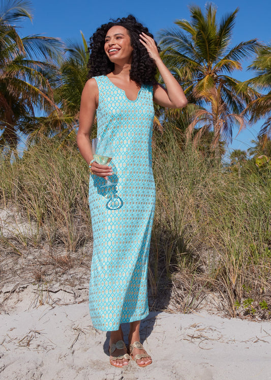 A woman holding dark curly hair in the wind and a wine glass on the beach while wearing the Aqua Metallic Side Slit Maxi Dress.