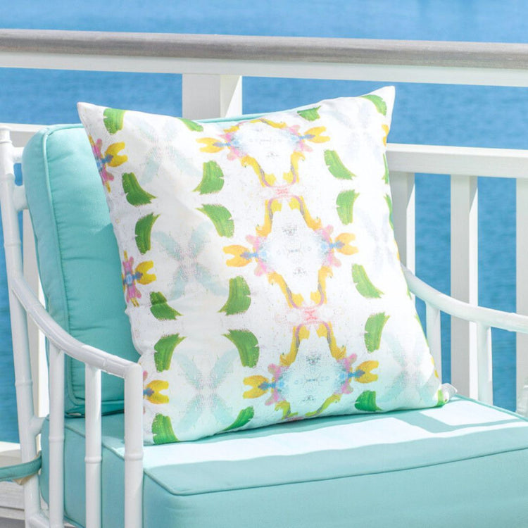 Decorative pillow with floral pattern on a white bench against a blue background