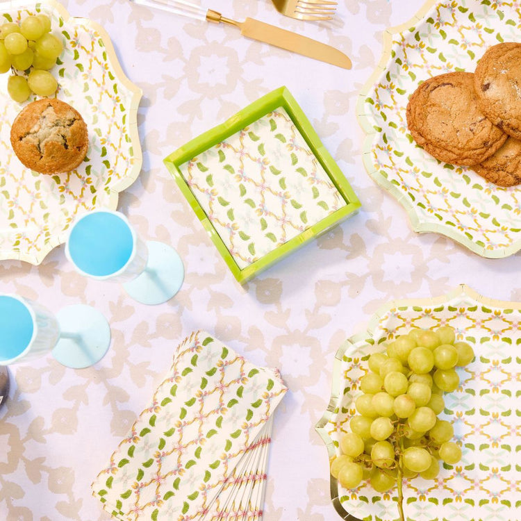 Table setting with patterned plates, grapes, cookies, and mugs on a textured surface.