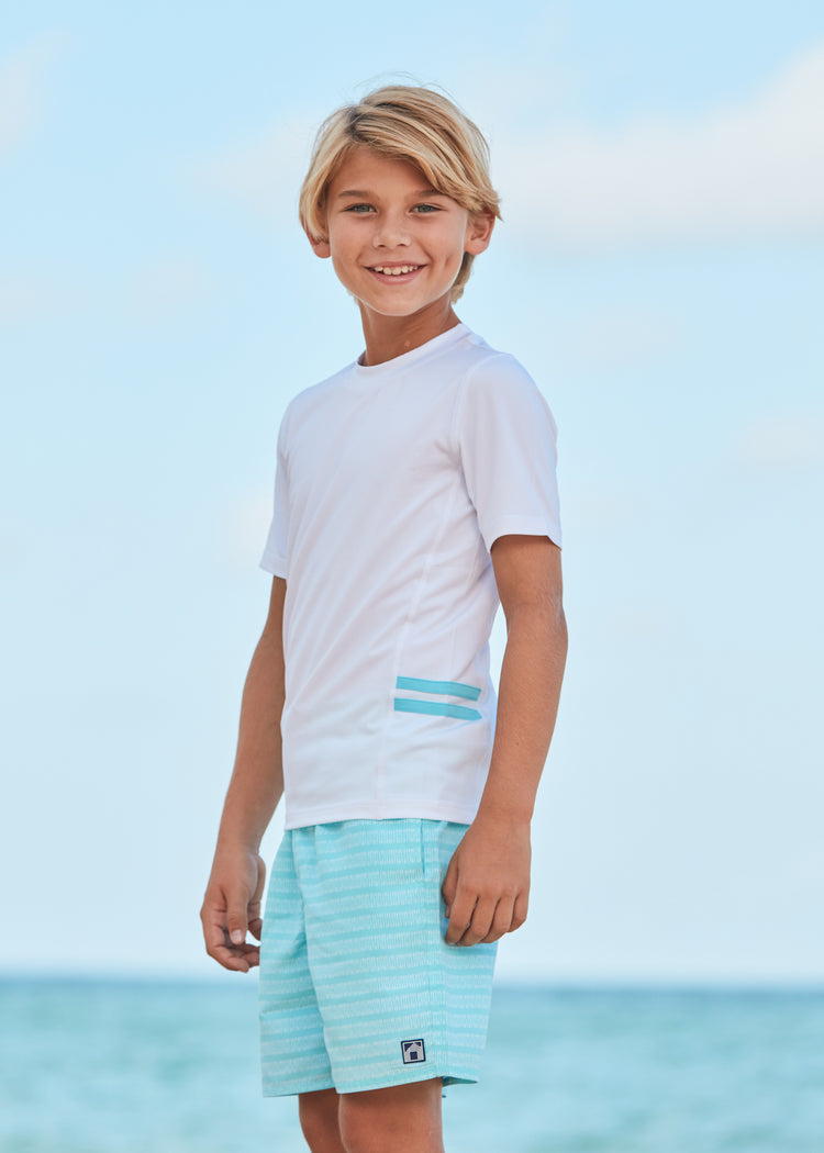 Boy wearing Naples Swim Trunks and White Short Sleeve Rashguard.